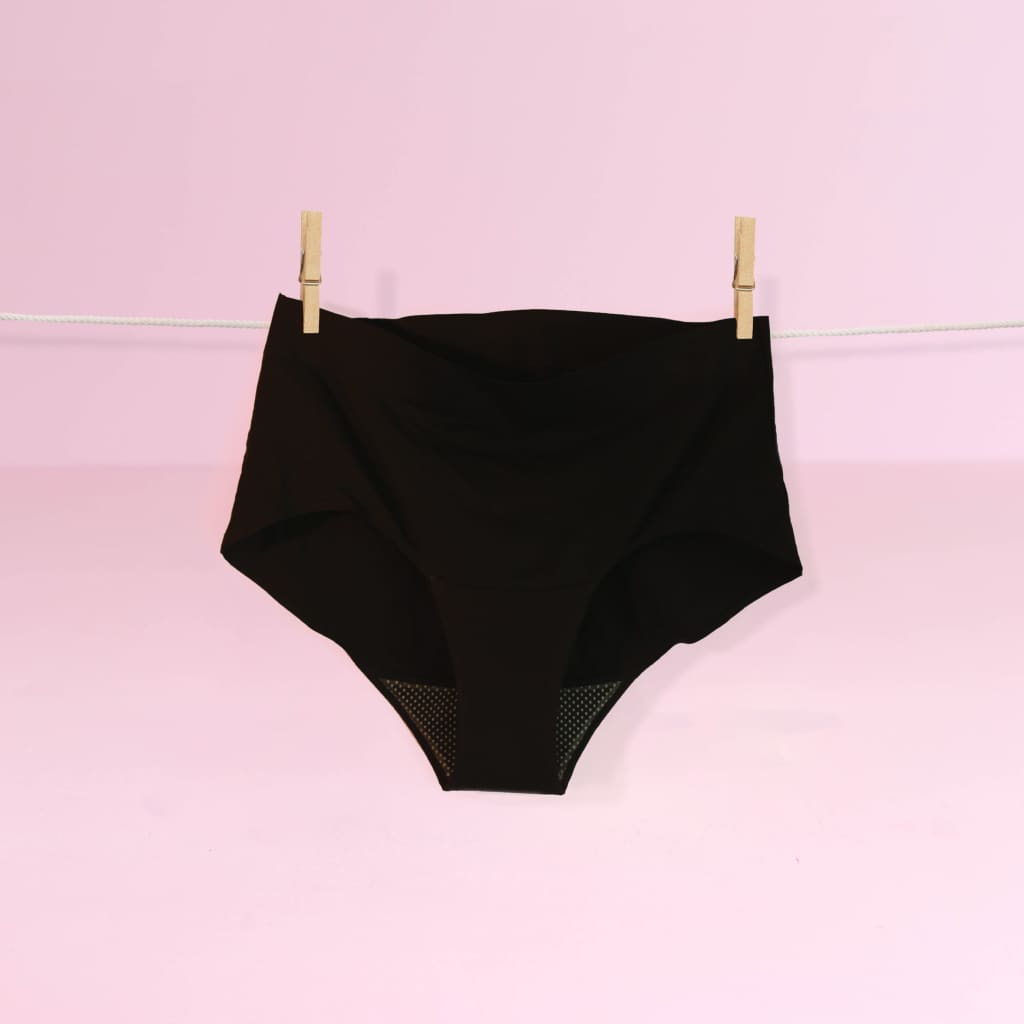 Black high-waisted underwear hanging on a clothesline against a pink background